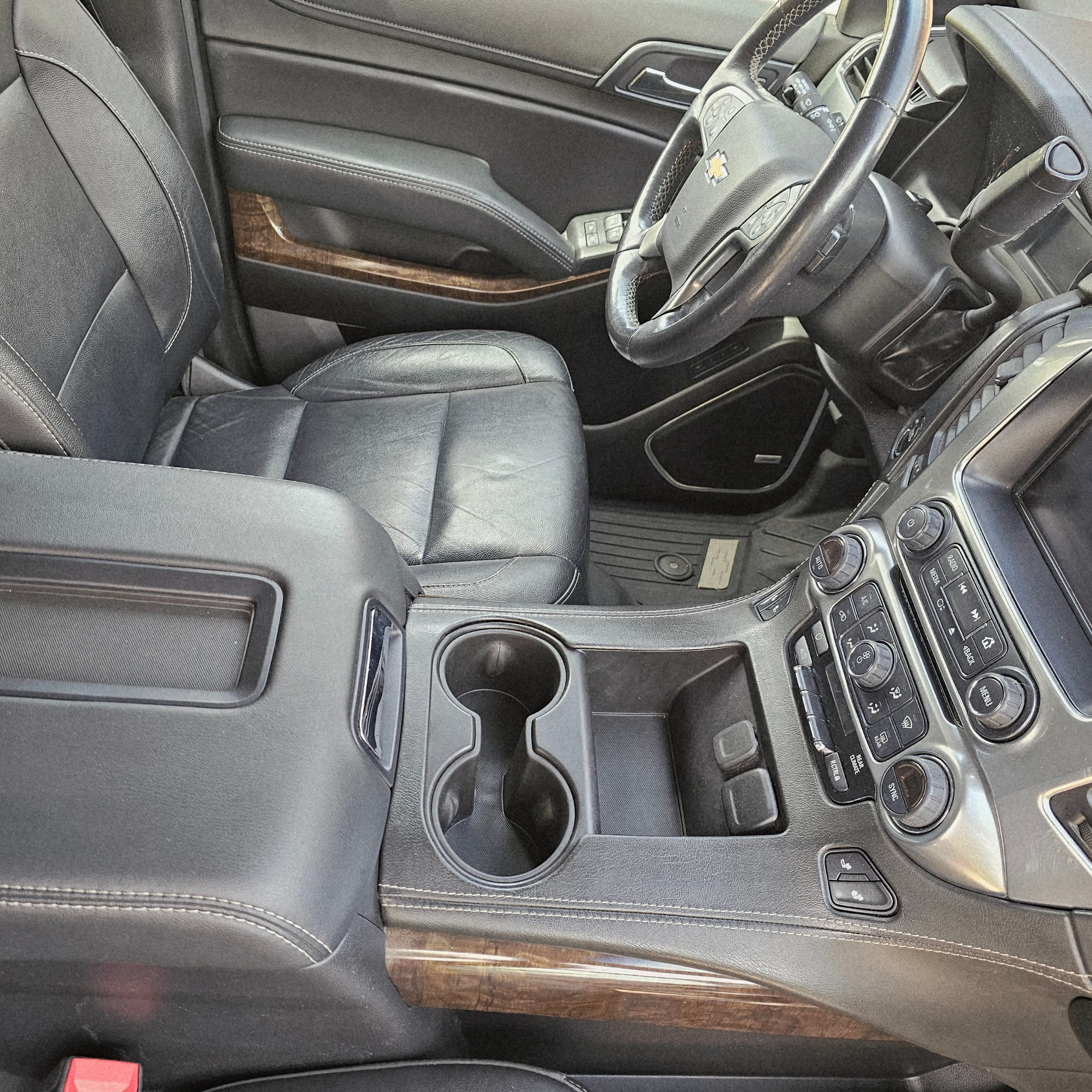 Clean Chevrolet Suburban center console, cup holders, leather seats, and dashboard after professional interior detailing.